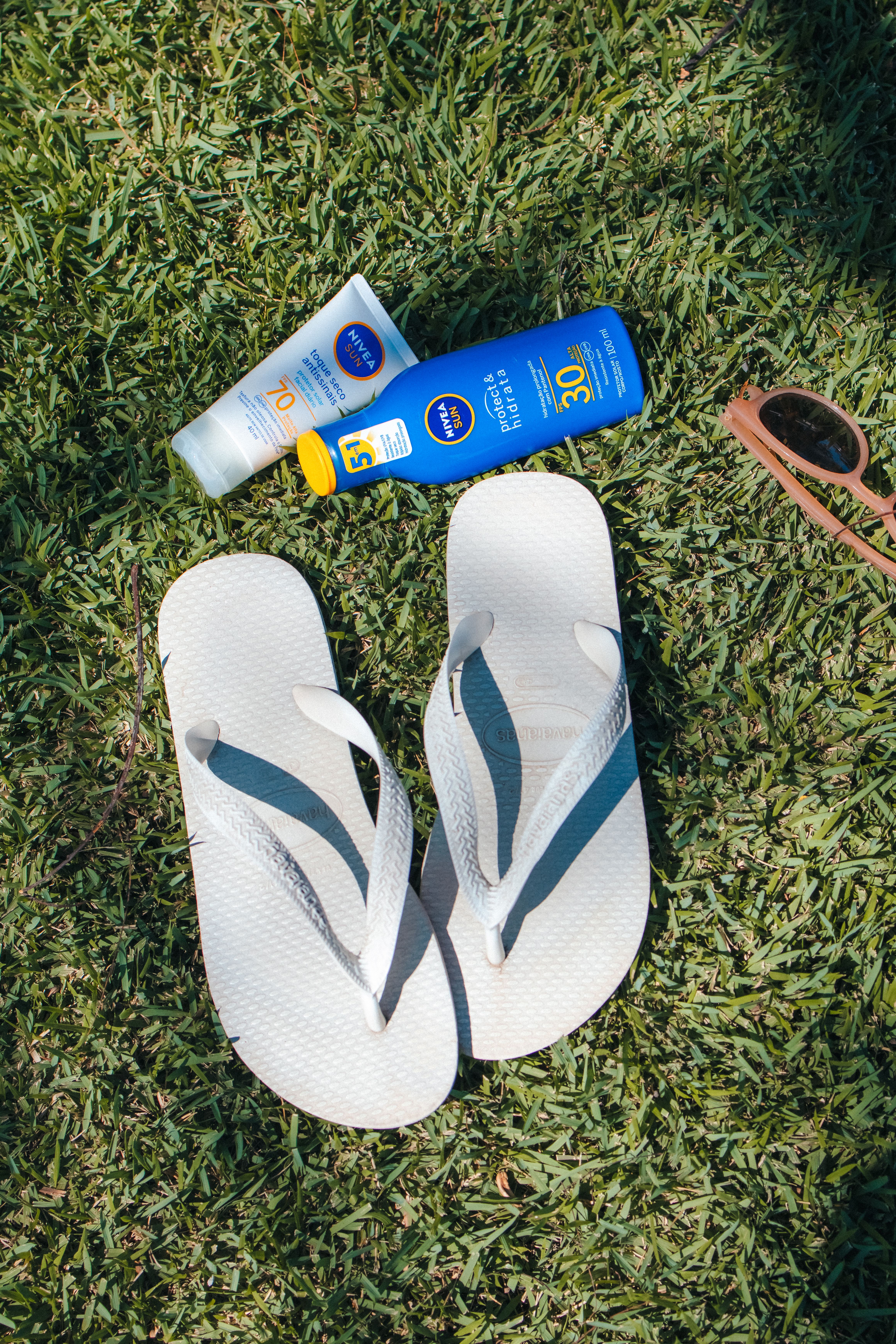 Protetor solar Nivea Sun FPS 70 ao lado de havaianas na grama